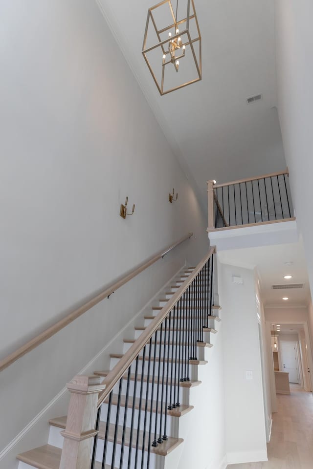 staircase with wood finished floors, visible vents, baseboards, a high ceiling, and recessed lighting