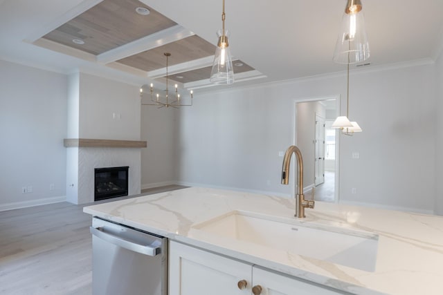 kitchen with pendant lighting, light stone counters, stainless steel dishwasher, white cabinetry, and a sink