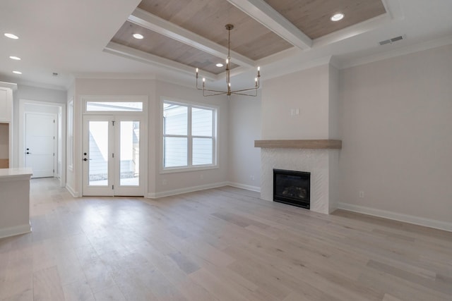 unfurnished living room featuring light wood finished floors, baseboards, a chandelier, beamed ceiling, and a tile fireplace