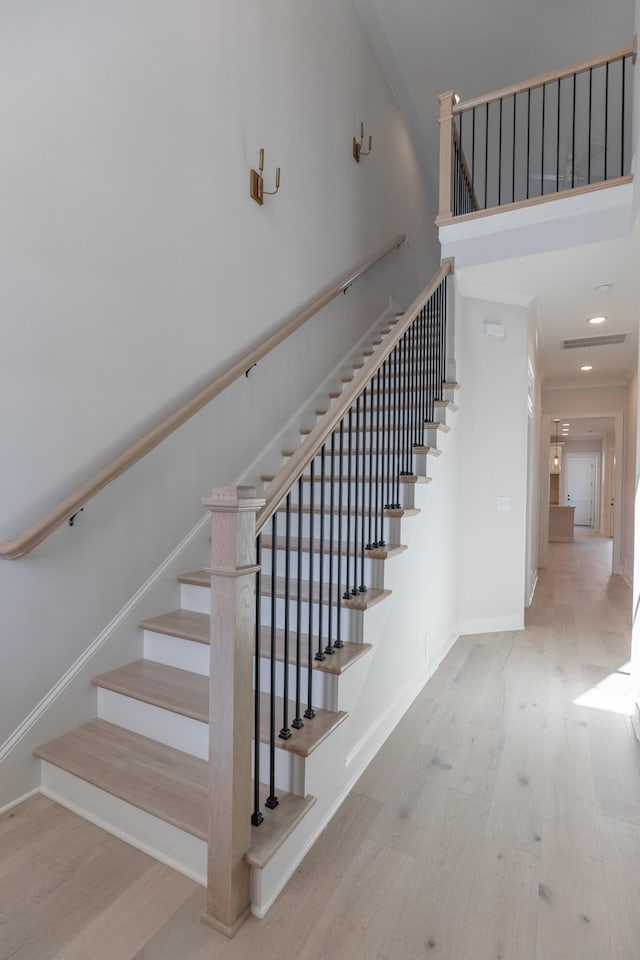 stairs featuring visible vents, wood finished floors, recessed lighting, a high ceiling, and baseboards