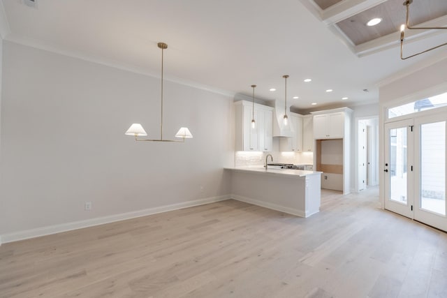 kitchen with a peninsula, light wood-type flooring, a wealth of natural light, and ornamental molding