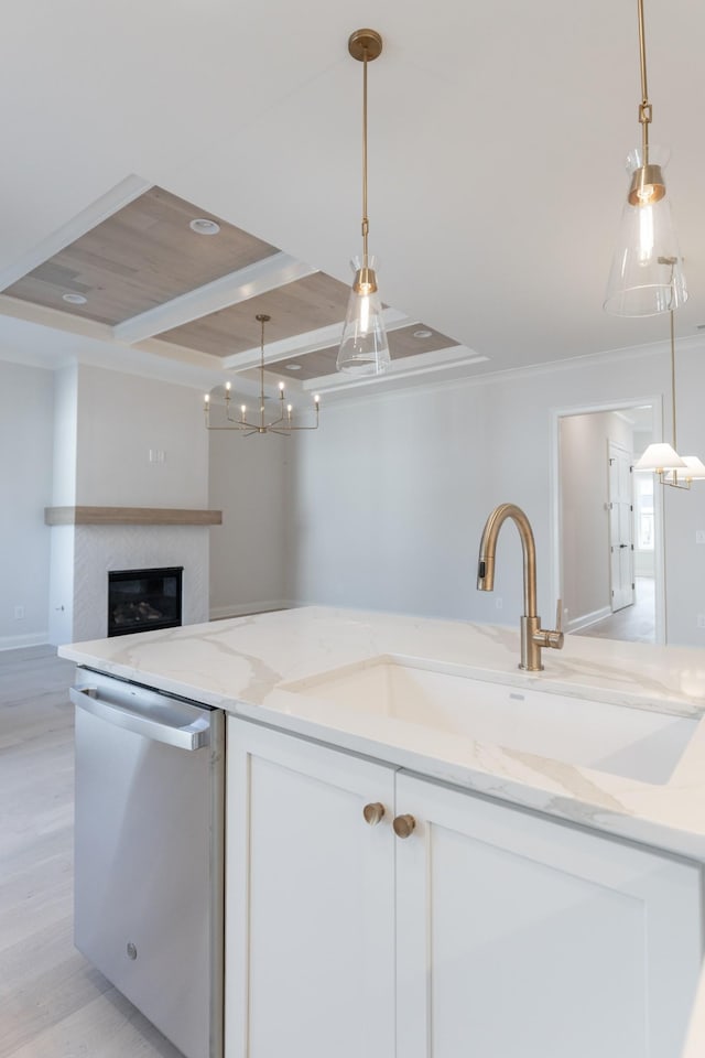 kitchen featuring a sink, decorative light fixtures, stainless steel dishwasher, and white cabinetry