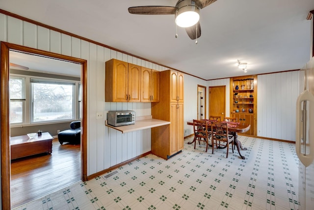 kitchen featuring built in shelves, ceiling fan, crown molding, white fridge, and light wood-type flooring