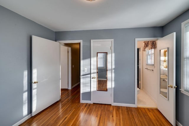 unfurnished bedroom featuring wood-type flooring and ensuite bath