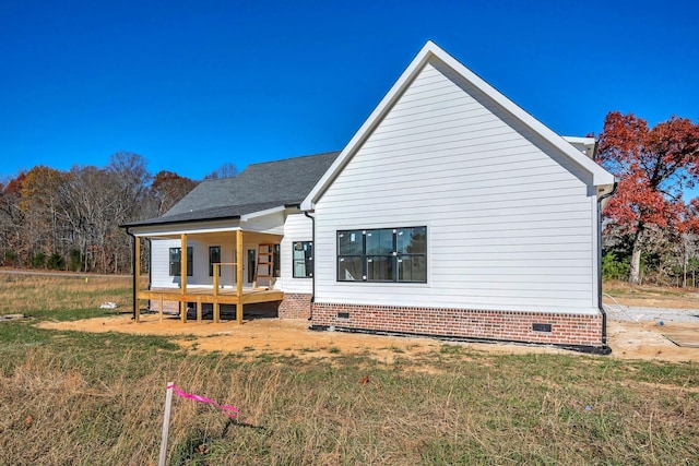 rear view of property featuring covered porch and a yard