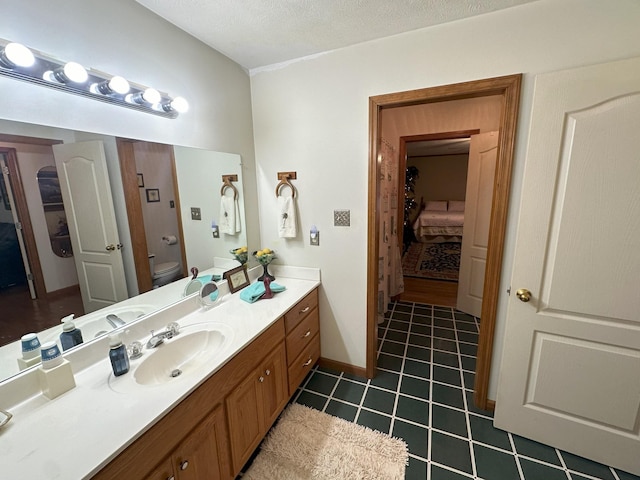 bathroom with tile patterned flooring, vanity, a textured ceiling, and toilet