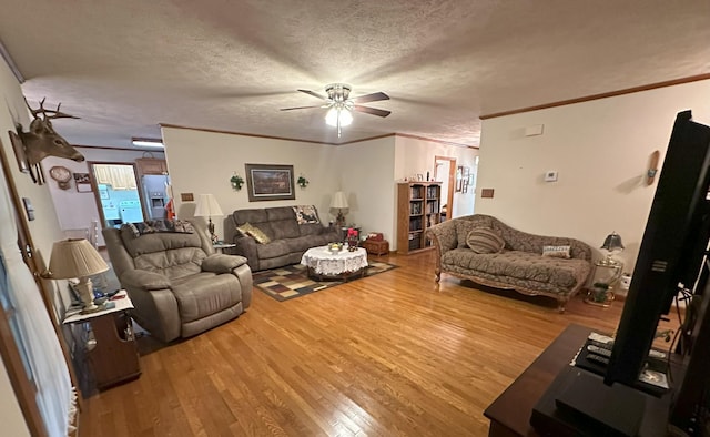 living room with wood-type flooring, a textured ceiling, ceiling fan, and ornamental molding