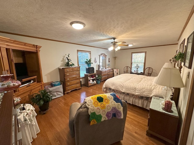 bedroom with hardwood / wood-style flooring, ceiling fan, ornamental molding, and a textured ceiling