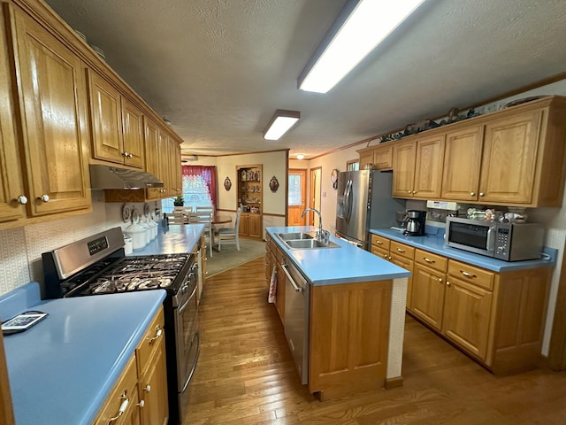 kitchen with sink, light wood-type flooring, a textured ceiling, an island with sink, and appliances with stainless steel finishes