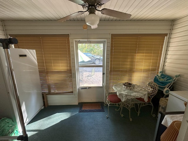 doorway with ceiling fan, carpet floors, wooden walls, and wooden ceiling