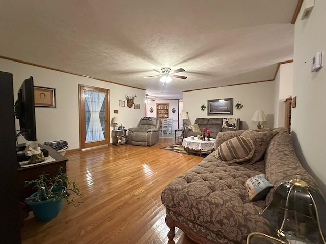 living room featuring ceiling fan, hardwood / wood-style floors, a textured ceiling, and ornamental molding