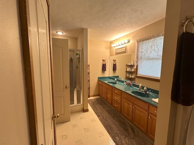 bathroom featuring vanity, an enclosed shower, and a textured ceiling