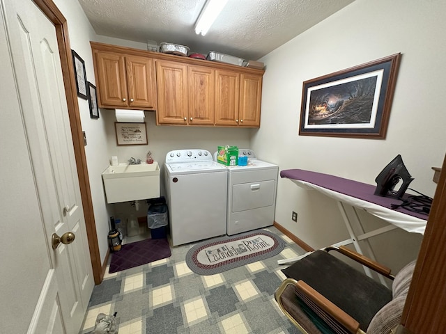 laundry area with washer and clothes dryer, cabinets, a textured ceiling, and sink