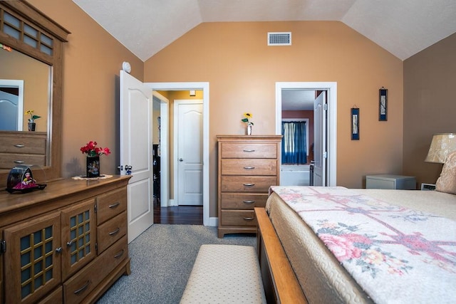 carpeted bedroom with ensuite bathroom and lofted ceiling