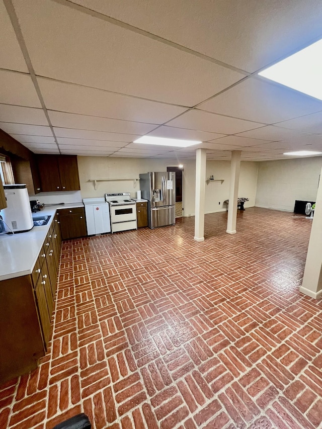 interior space with a paneled ceiling, stainless steel fridge, dark brown cabinetry, and white electric range oven