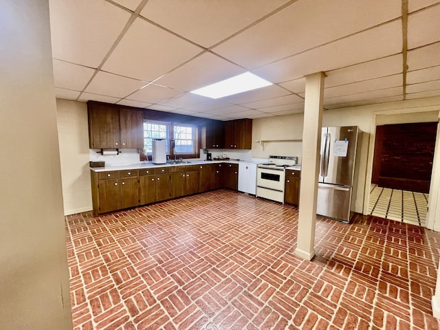 kitchen with white range with electric stovetop, a paneled ceiling, stainless steel fridge, and dark brown cabinets