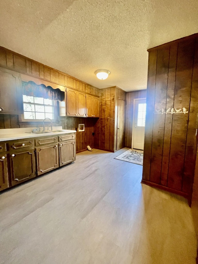 kitchen featuring wood walls, a textured ceiling, a healthy amount of sunlight, and sink