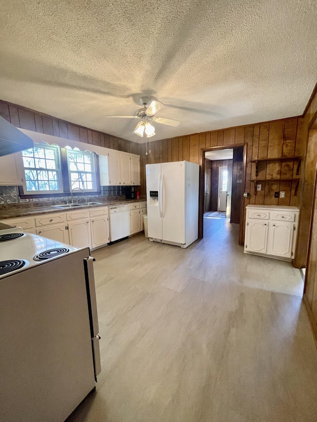 kitchen with ceiling fan, wood walls, a textured ceiling, white appliances, and white cabinets