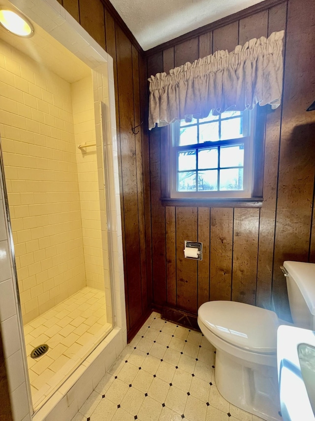 bathroom with a tile shower, wooden walls, and toilet