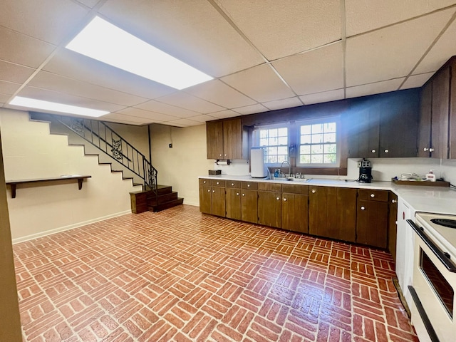 kitchen with sink, a drop ceiling, dark brown cabinets, and white electric range