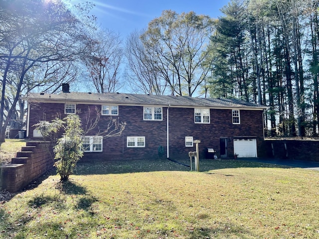 rear view of property with a garage and a lawn