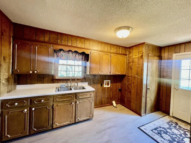 kitchen featuring a textured ceiling, wooden walls, a healthy amount of sunlight, and sink