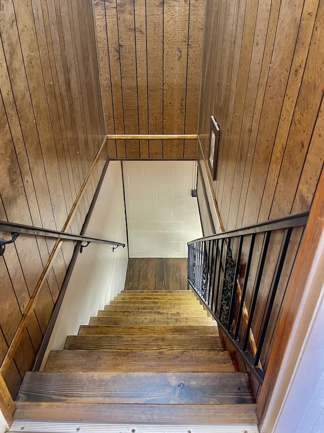 staircase featuring hardwood / wood-style floors and wooden walls