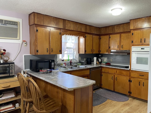 kitchen with sink, an AC wall unit, light hardwood / wood-style floors, a textured ceiling, and black appliances