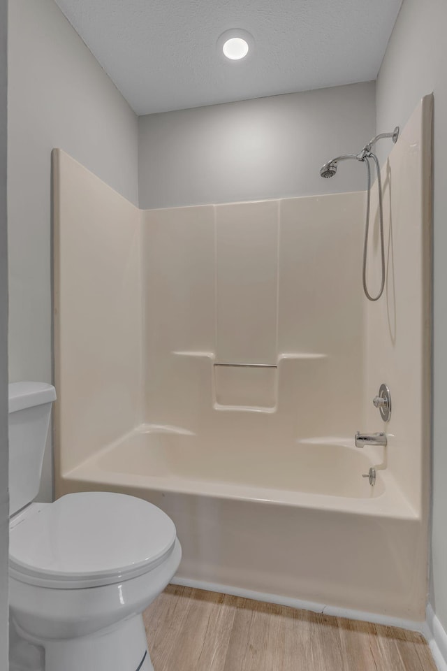 bathroom featuring hardwood / wood-style floors, shower / bath combination, a textured ceiling, and toilet