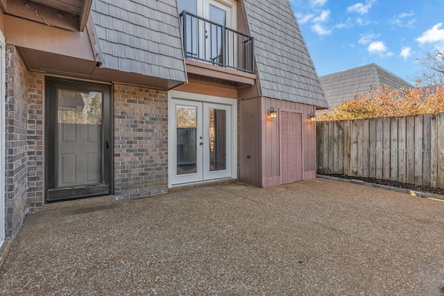 entrance to property featuring french doors, a balcony, and a patio area