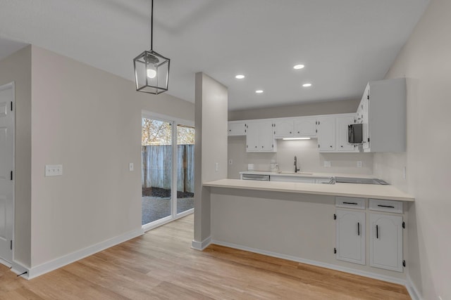 kitchen with white cabinetry, sink, hanging light fixtures, light hardwood / wood-style floors, and black electric stovetop