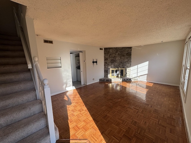 unfurnished living room featuring a fireplace, parquet flooring, and a textured ceiling