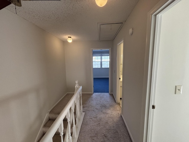 corridor with light carpet and a textured ceiling