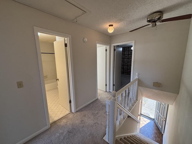 hallway with light carpet and a textured ceiling