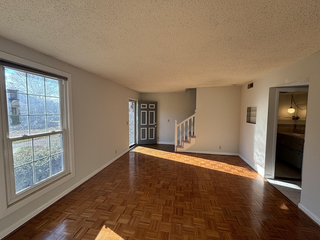 unfurnished room featuring dark parquet flooring and a textured ceiling