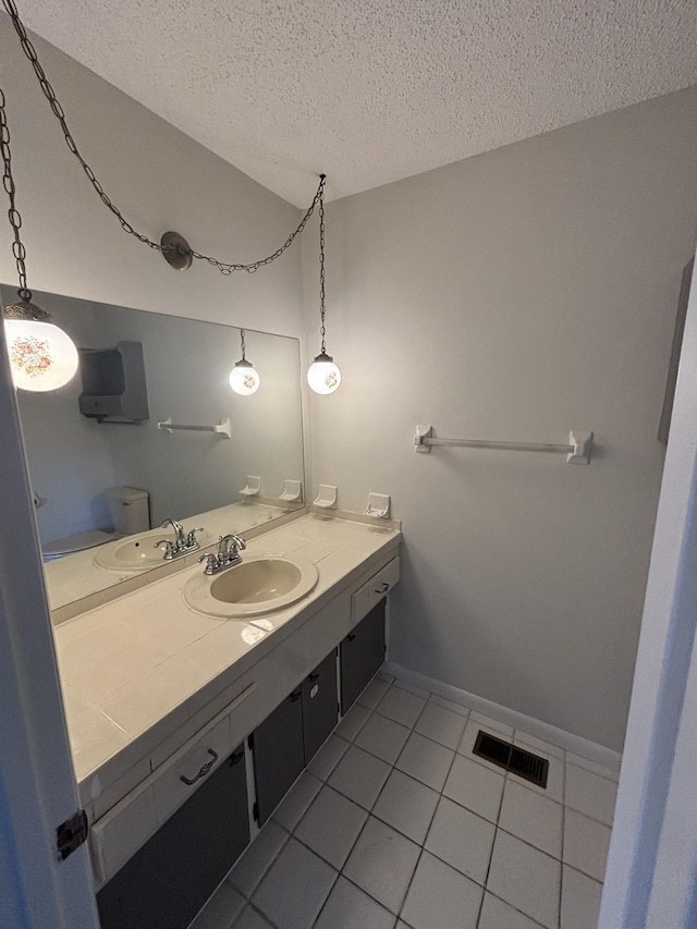 bathroom with vanity, a textured ceiling, and tile patterned floors