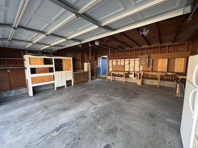 garage with a garage door opener and white refrigerator