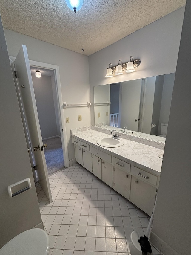 bathroom with tile patterned floors, vanity, a textured ceiling, and toilet