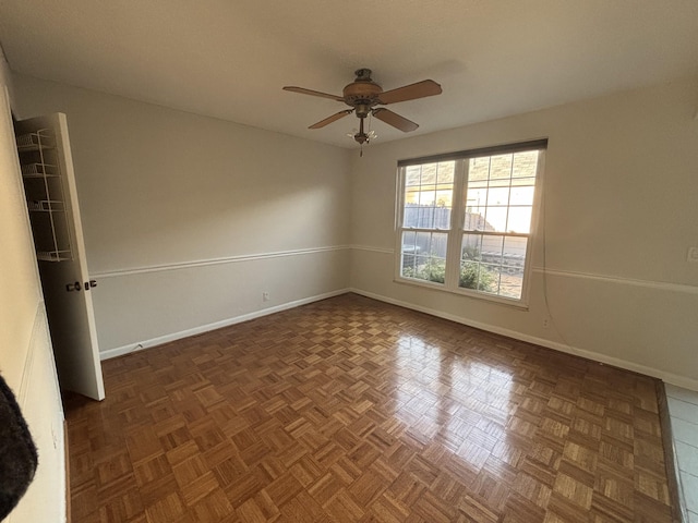 unfurnished room with ceiling fan and dark parquet floors