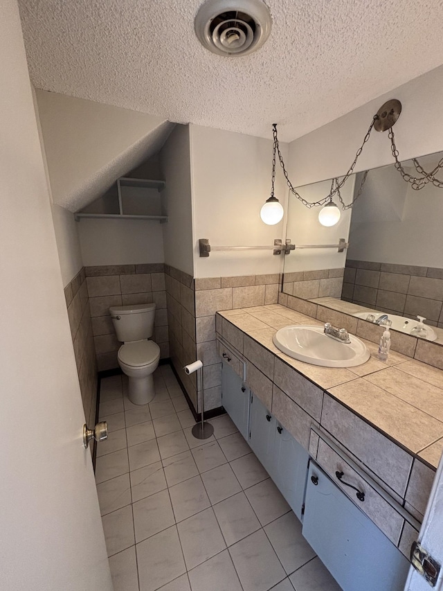 bathroom featuring toilet, a textured ceiling, tile patterned floors, and tile walls