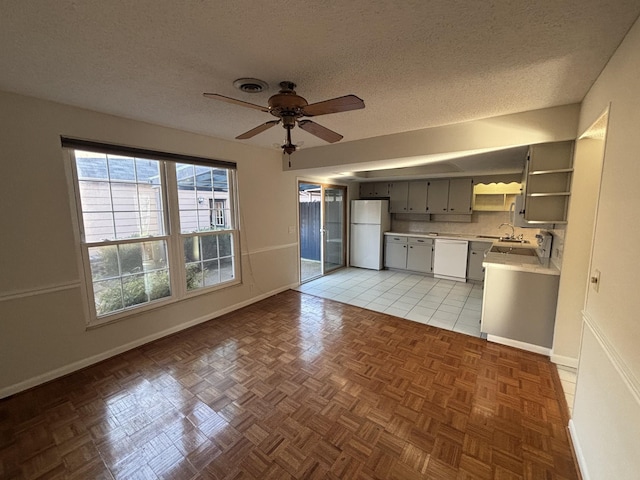 kitchen featuring white appliances, ceiling fan, gray cabinets, light tile patterned floors, and a textured ceiling