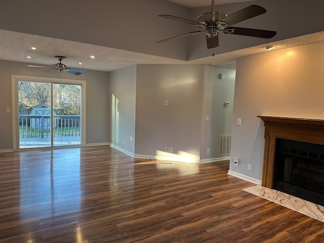 unfurnished living room featuring a fireplace, a textured ceiling, ceiling fan, and dark wood-type flooring