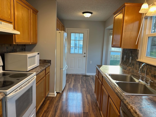 kitchen with sink, dark wood-type flooring, tasteful backsplash, pendant lighting, and white appliances