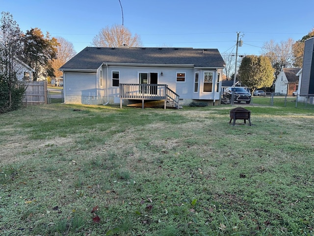 rear view of property featuring a fire pit, a lawn, and a wooden deck