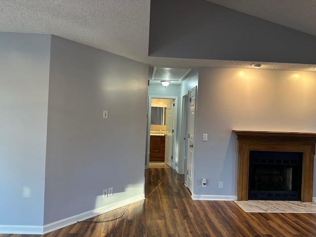 unfurnished living room featuring dark hardwood / wood-style flooring, lofted ceiling, and a textured ceiling