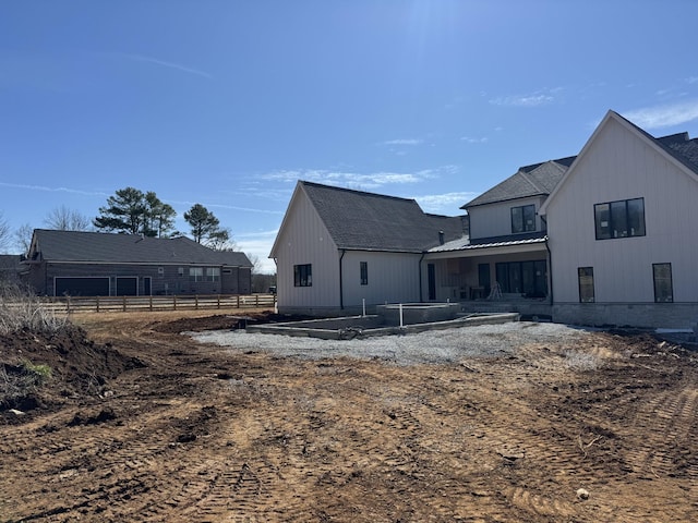 rear view of house featuring metal roof, a standing seam roof, and fence