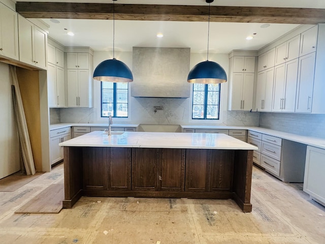 kitchen with tasteful backsplash, light countertops, a sink, and wall chimney exhaust hood