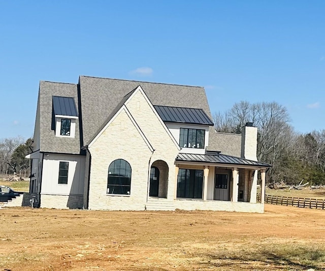 view of front of home featuring board and batten siding, a standing seam roof, roof with shingles, and metal roof