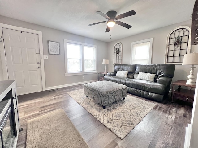 living room with a wealth of natural light, dark hardwood / wood-style flooring, and ceiling fan