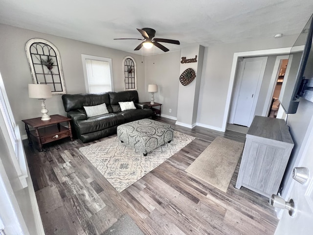 living room featuring ceiling fan and dark wood-type flooring